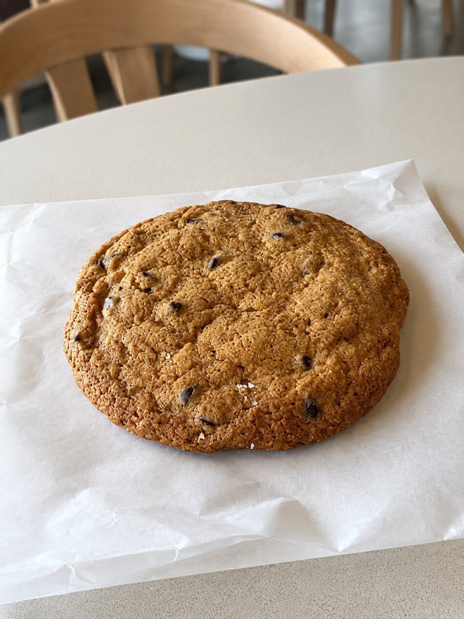 A large chocolate chip cookie on parchment at Vici Café